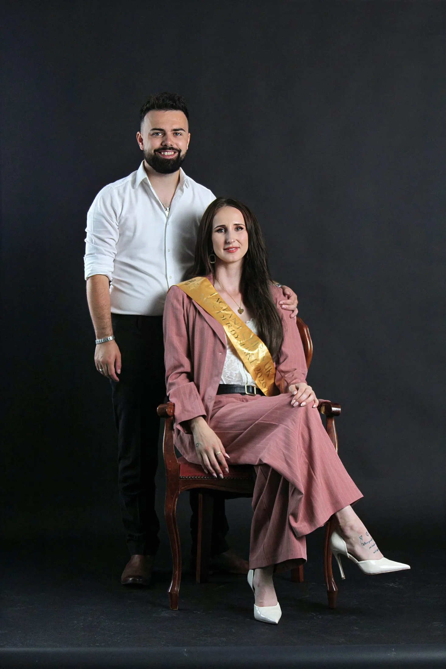Emma, seated in a pink pinstripe suit and gold Miss Derbyshire 2026 sash, with her sponsor Brad, owner of Printlogik Ltd