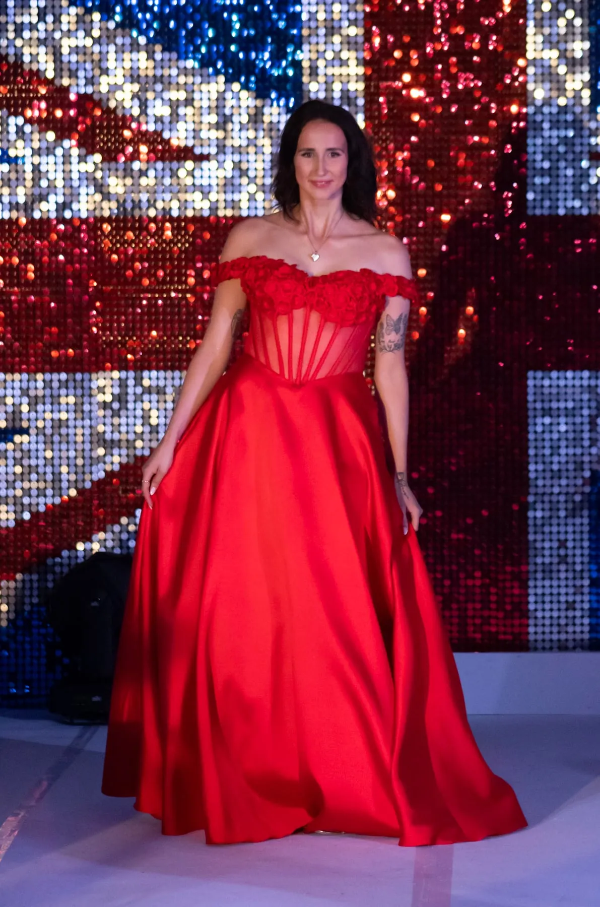 Emma on the national final stage in a red gown in front of a sequinned Union Jack